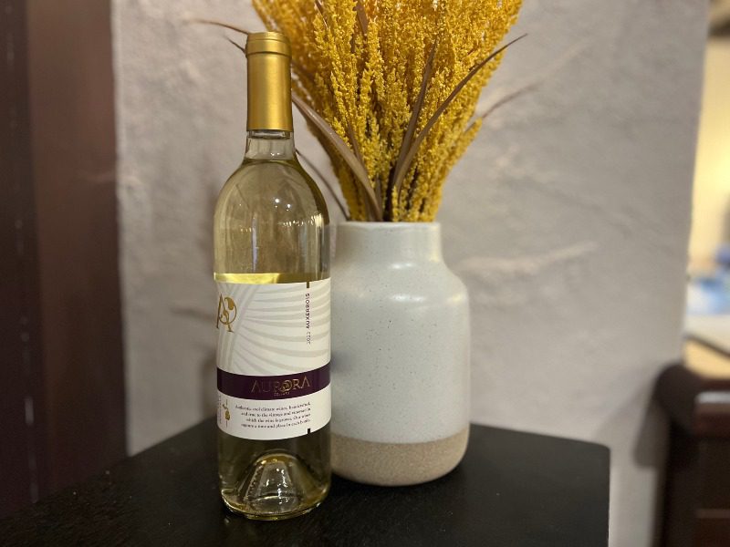 Bottle of Aurora Cellars white wine beside a vase with yellow florals in Lake Leelanau, MI  