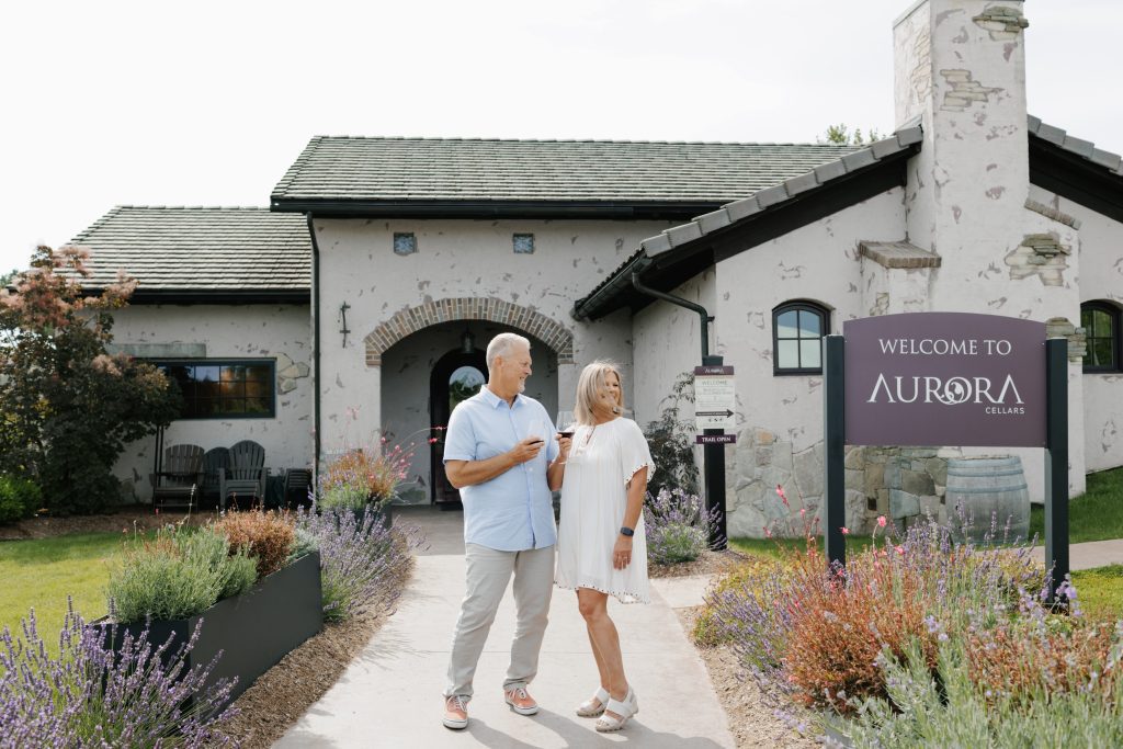 A couple stands in front of Lake Leelanau, MI, a well-liked summer event, Returns to Aurora Cellars