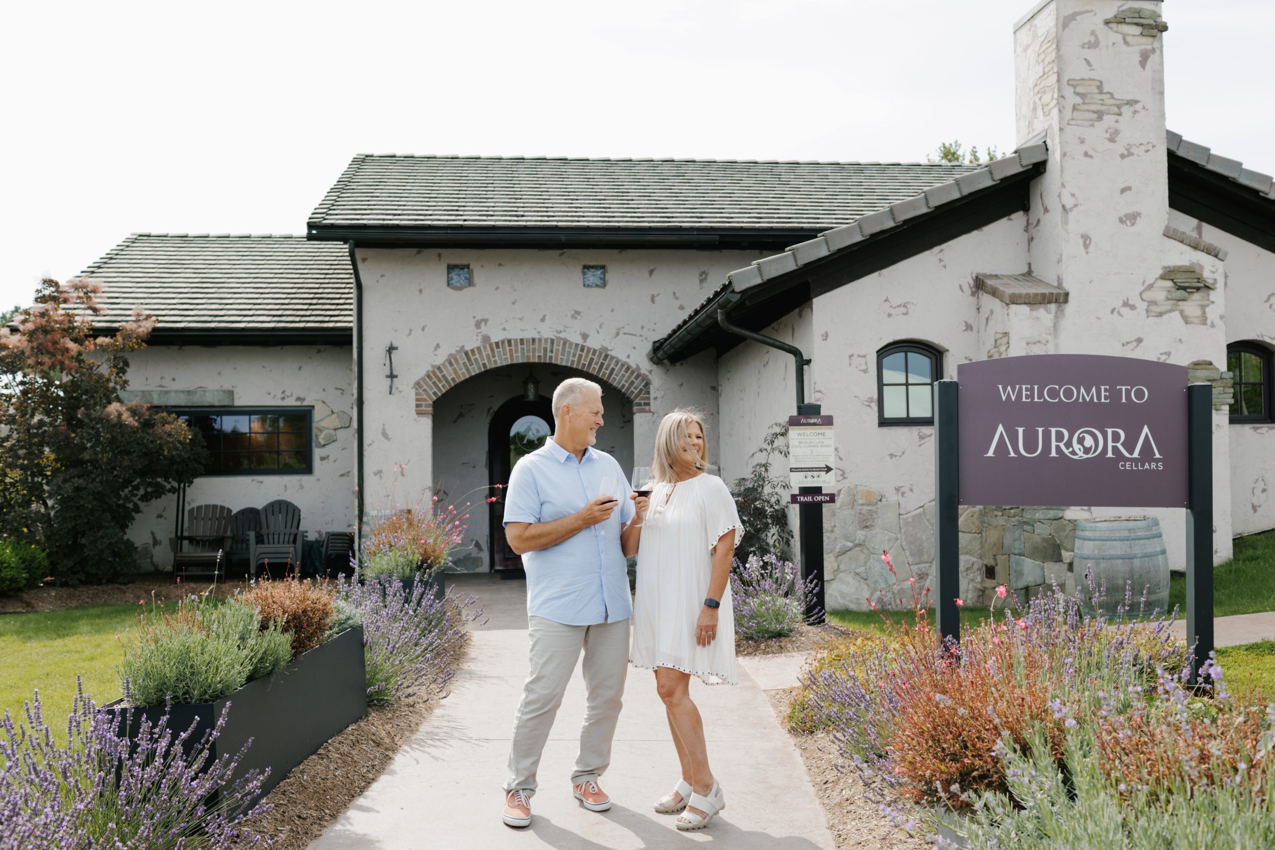 A couple stands in front of Lake Leelanau, MI, a well-liked summer event, Returns to Aurora Cellars